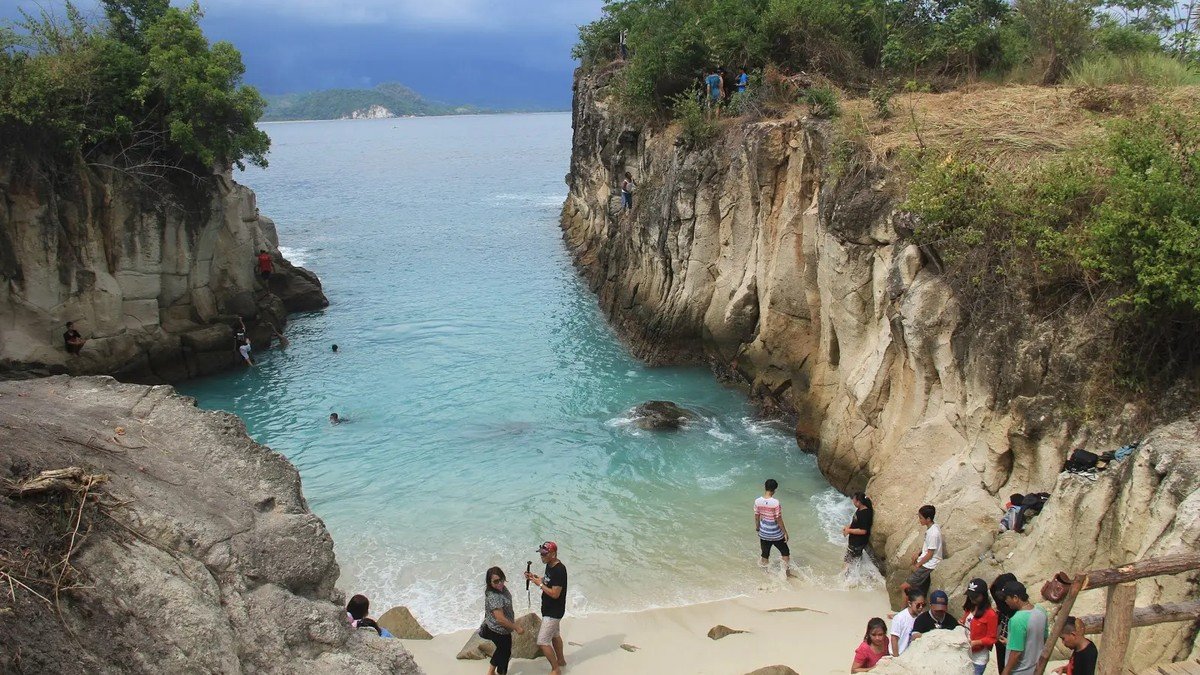 formasi batuan unik di Pantai Ratatotok Manado dengan latar air laut dan vegetasi hijau alami