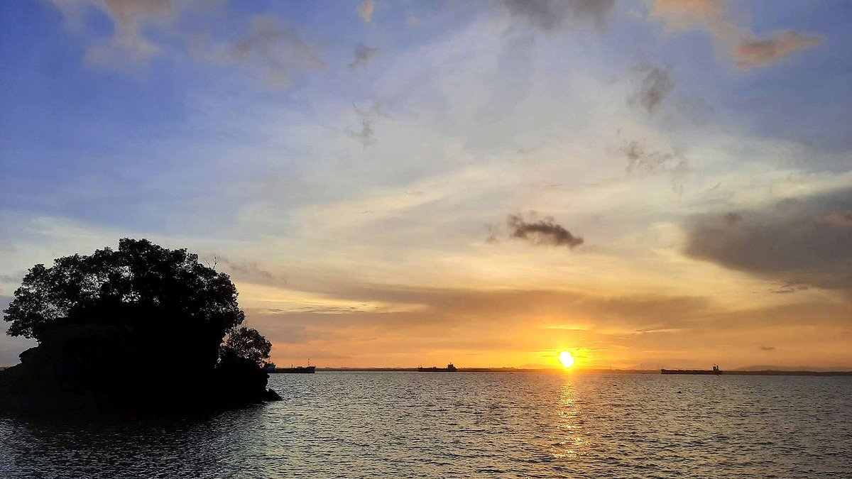 Sunset di Pantai Melawai Balikpapan dengan pemandangan kapal tanker di laut dan pedagang kaki lima di tepi pantai