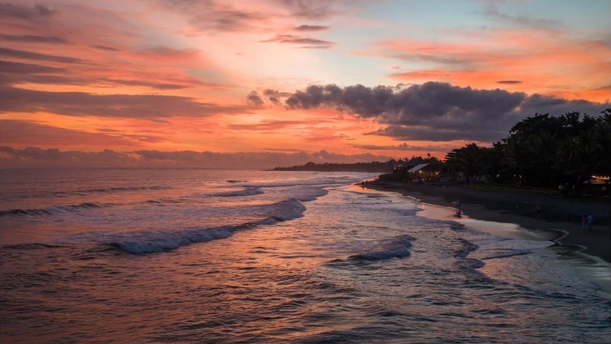 Pemandangan tebing dan laut lepas Samudra Hindia dari Pantai Karang Tawulan saat matahari terbenam