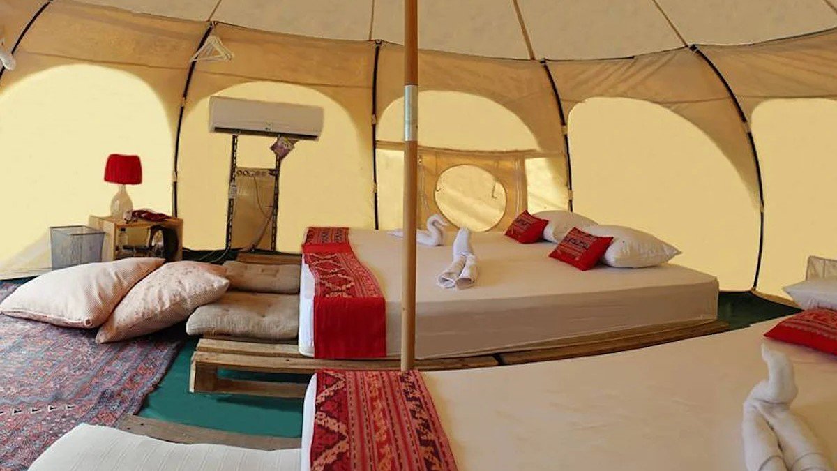 Interior tenda glamping di Sukabumi dengan fasilitas lengkap, kasur, dan pencahayaan hangat