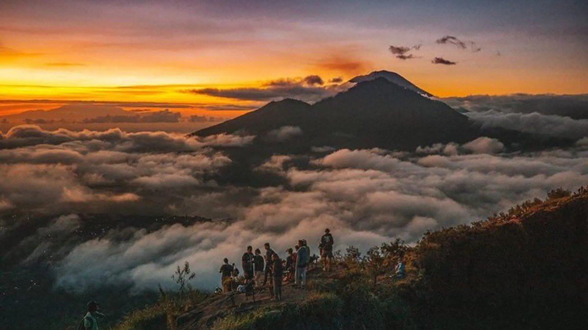 Pendaki di puncak Gunung Batur dengan latar Danau Batur dan kaldera luas saat sunrise
