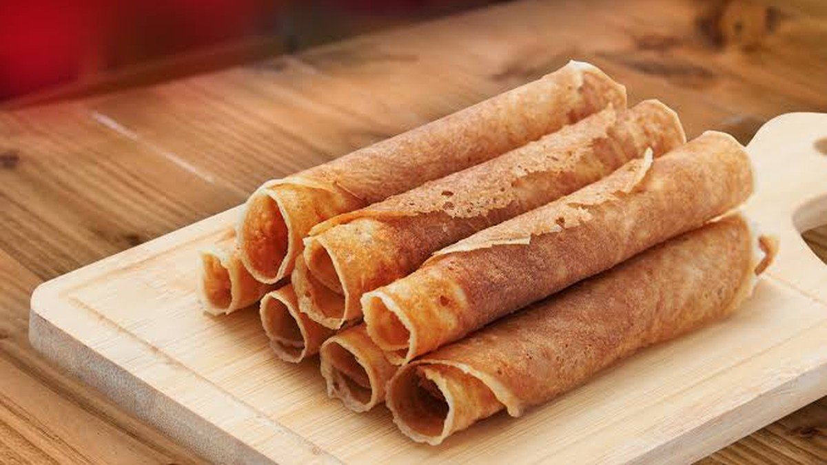 Kuih kapit atau kapit biskuit tipis berlipat dalam toples kemasan oleh-oleh Malaysia