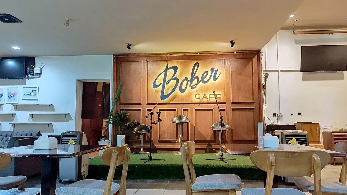 Interior vintage Bober Cafe Bandung yang hangat dengan pencahayaan kuning dan pengunjung yang nongkrong larut malam