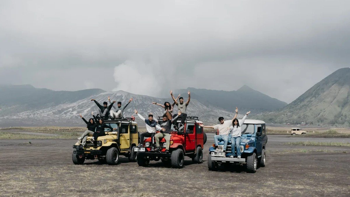 Jeep 4×4 private paket wisata Bromo melintasi lautan pasir dengan kawah Bromo di latar belakang