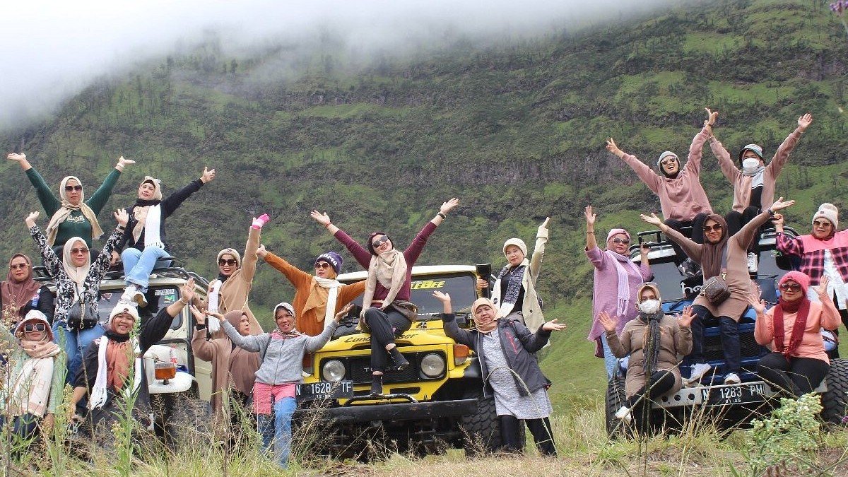 Wisatawan menggunakan jasa Nahwa Tour untuk paket wisata Bromo dengan jeep merah di kawasan lautan pasir