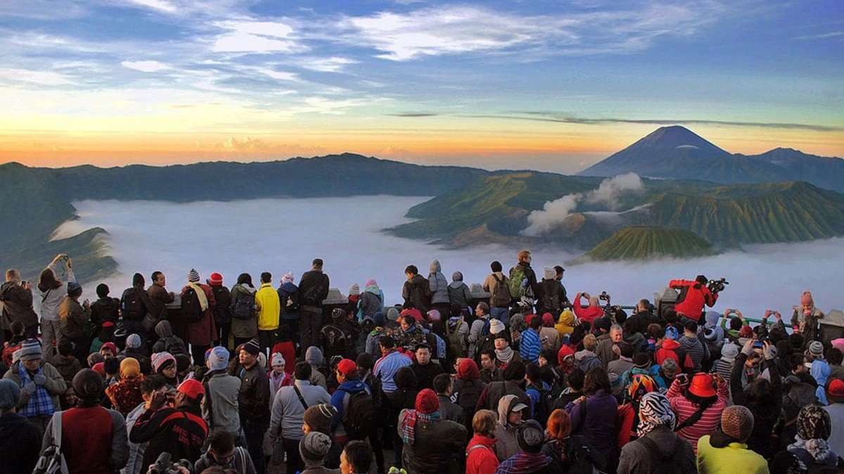 Golden sunrise dari Penanjakan 1 kawasan paket wisata Bromo dengan lautan awan dan kawah mengepul